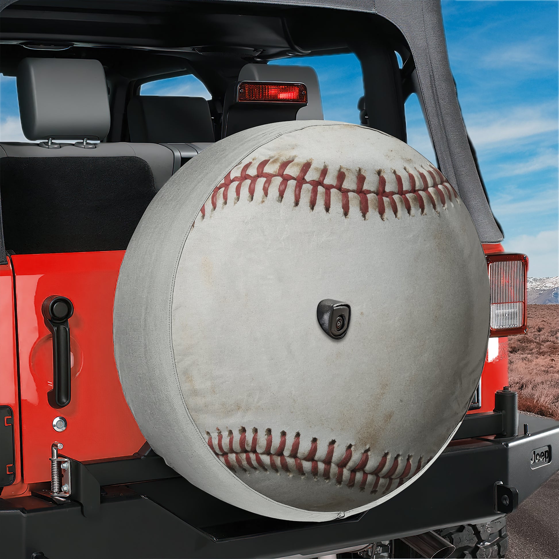 A red Jeep Wrangler with a large, white baseball-shaped spare tire attached to the rear.