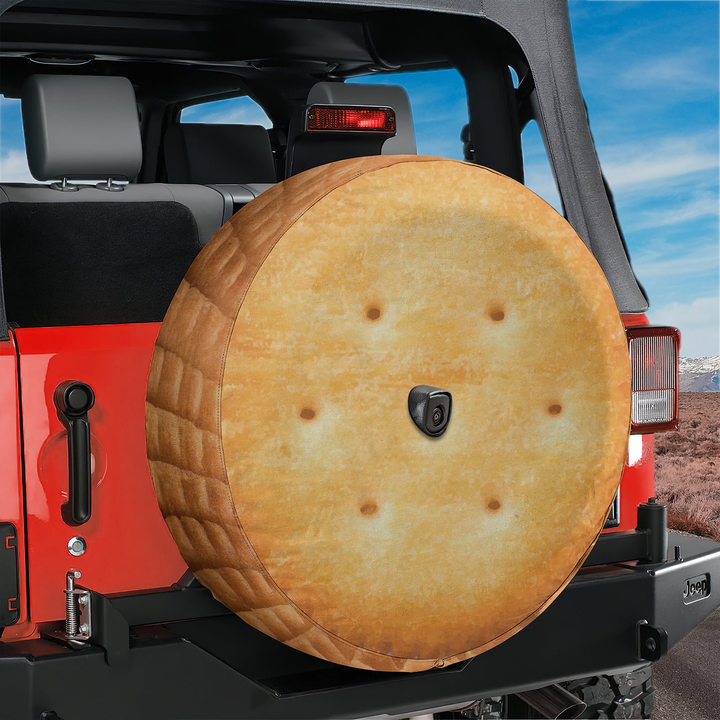 A red Jeep Wrangler with a large, round spare tire attached to the rear.