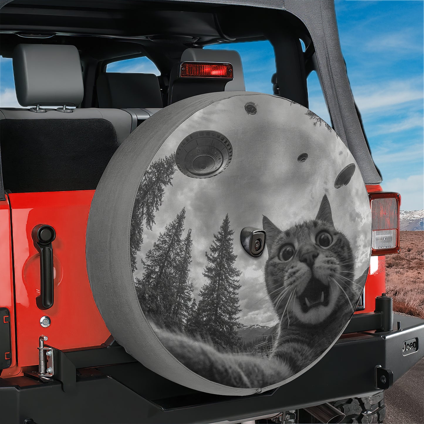 A black and white image of a cat with a surprised expression on its face, surrounded by trees and mountains, is displayed on the rear of a red Jeep.