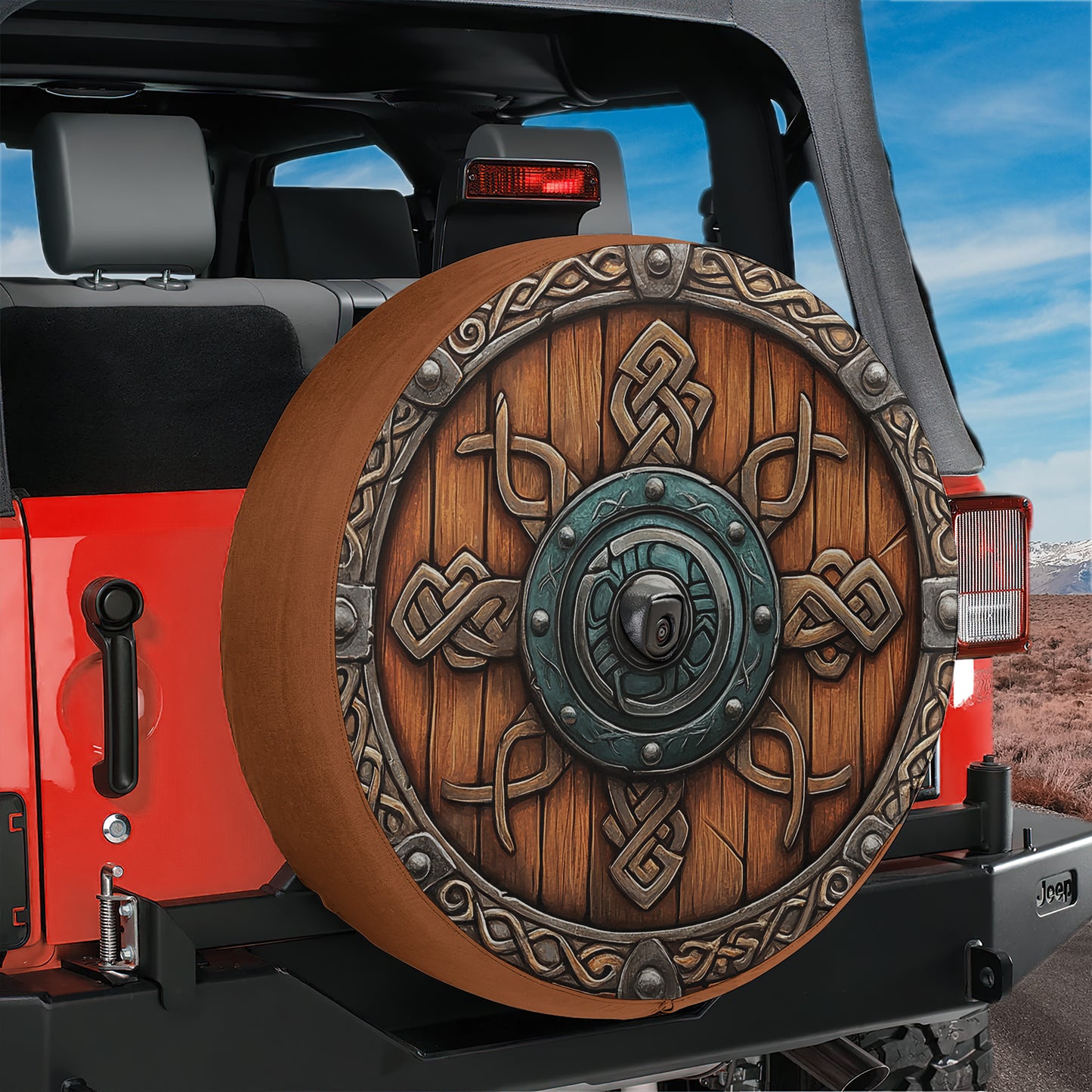 A red Jeep with a large, ornate wheel cover featuring intricate designs and patterns.