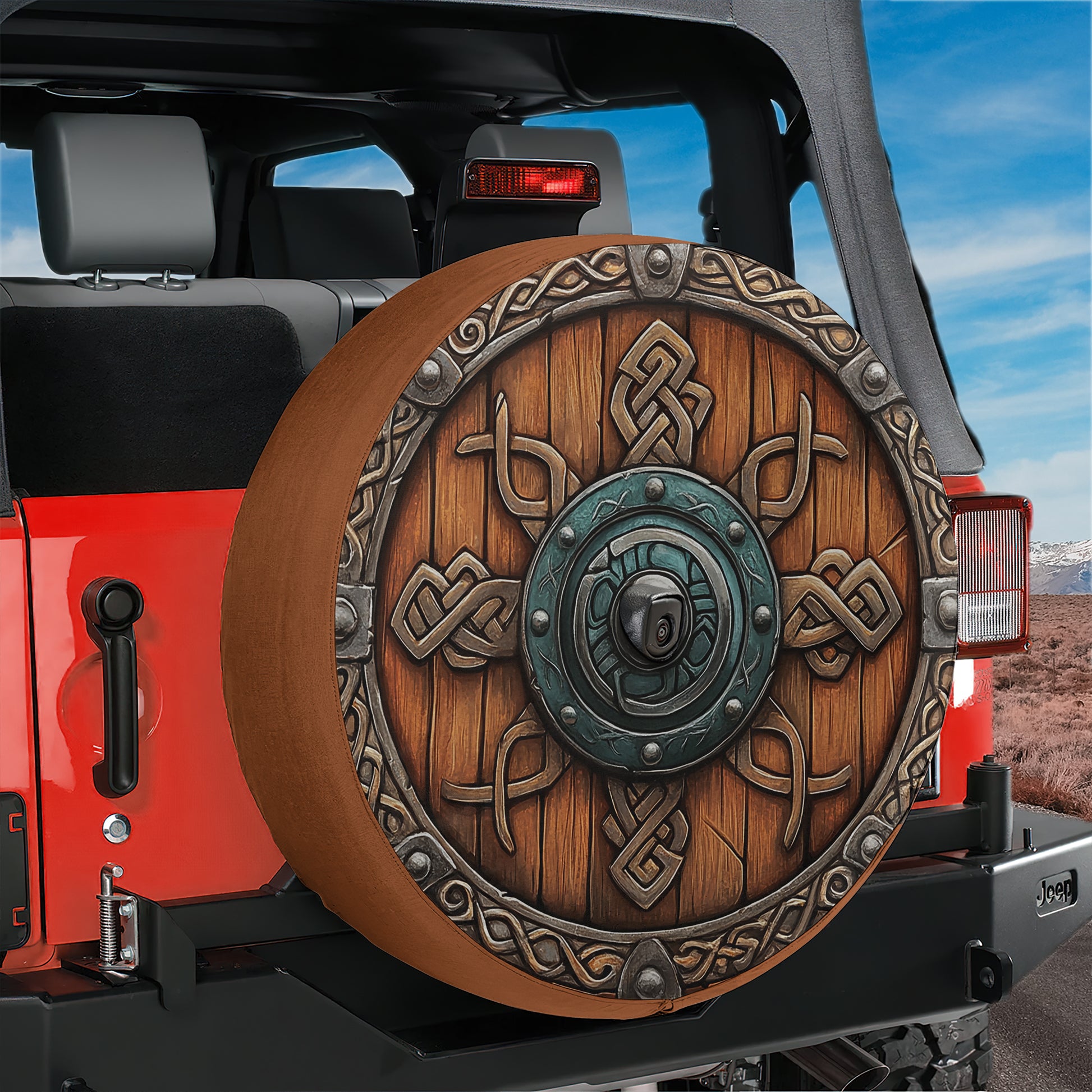 A red Jeep with a large, ornate wheel cover featuring intricate designs and patterns.