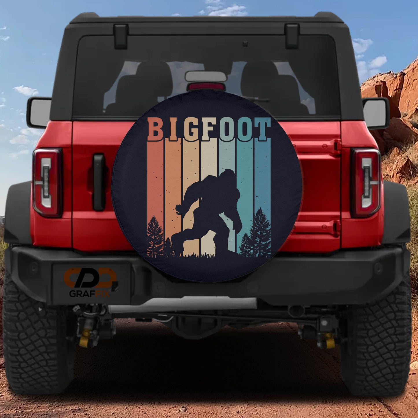 a red Jeep Wrangler with a large tire cover on the rear of the vehicle. The cover displays a silhouette of a Sasquatch, a mythical creature from the American West, along with the text "BIGFOOT".