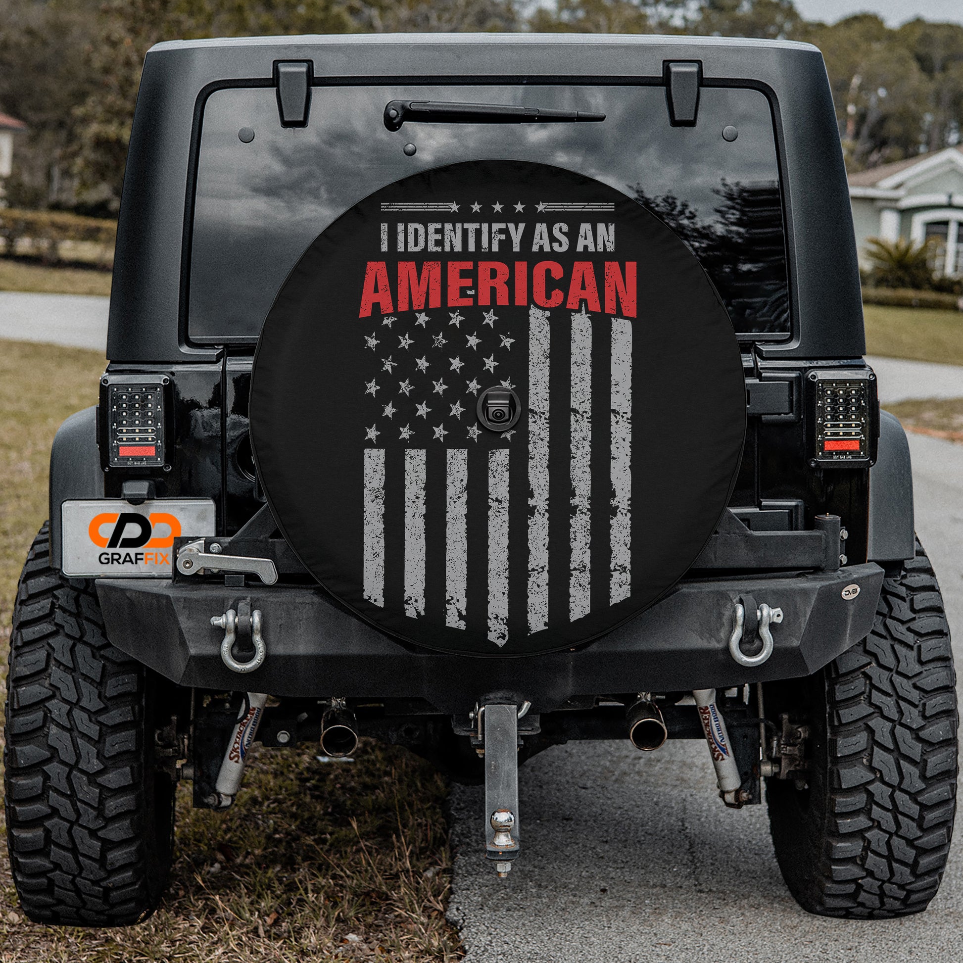 a black Jeep Wrangler with a large American flag decal on the rear window.