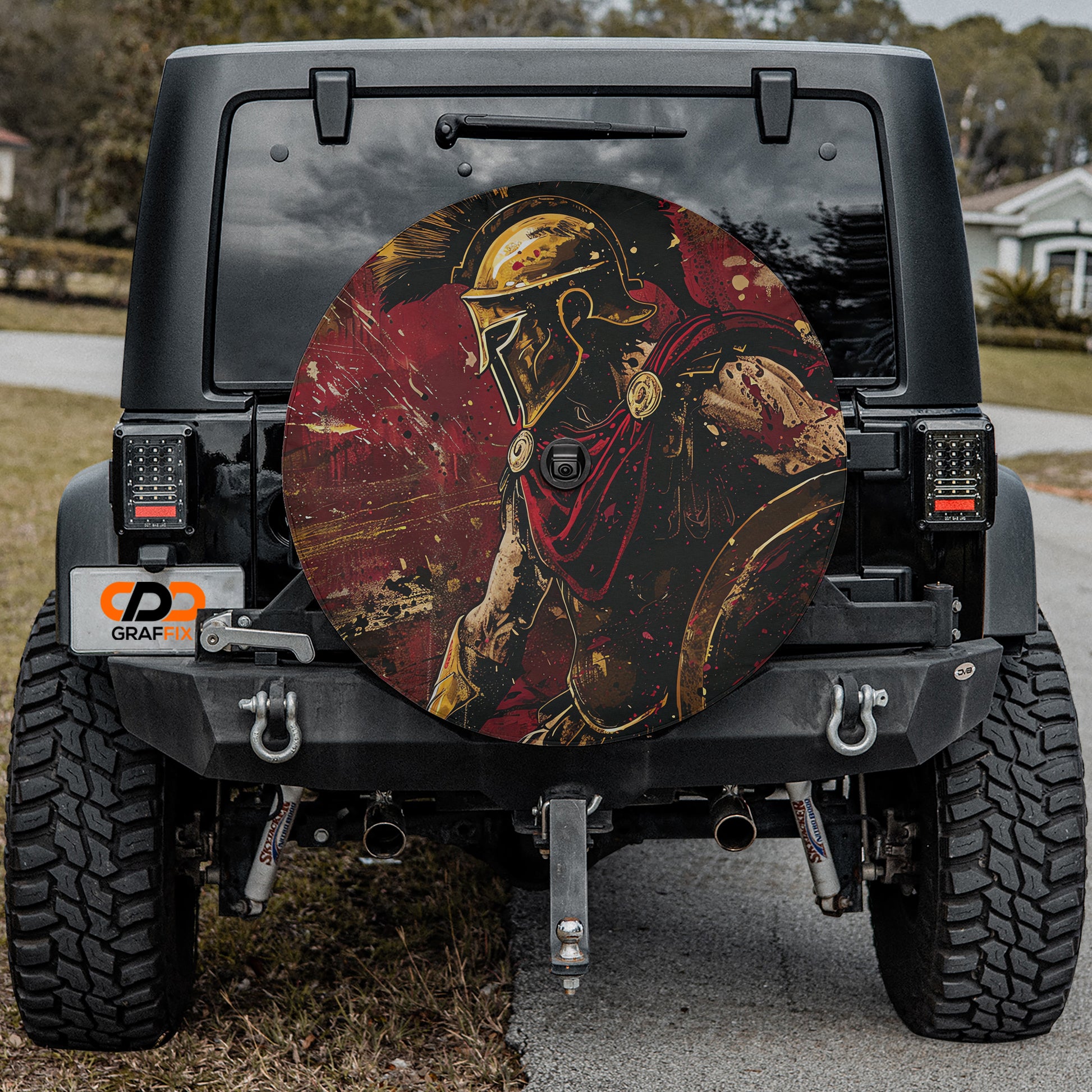 the back of a black Jeep Wrangler with a large, circular decal featuring a warrior figure in red and gold colors.