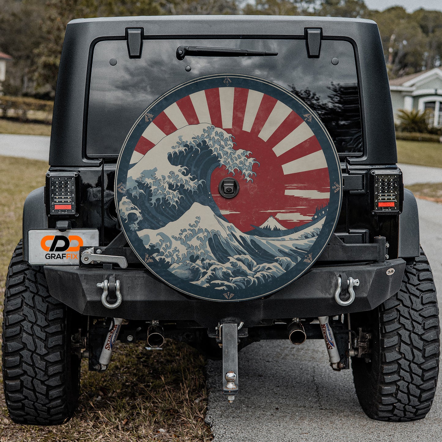 the rear of a black Jeep Wrangler with a large, colorful wheel cover featuring a wave design and a red and white sun.
