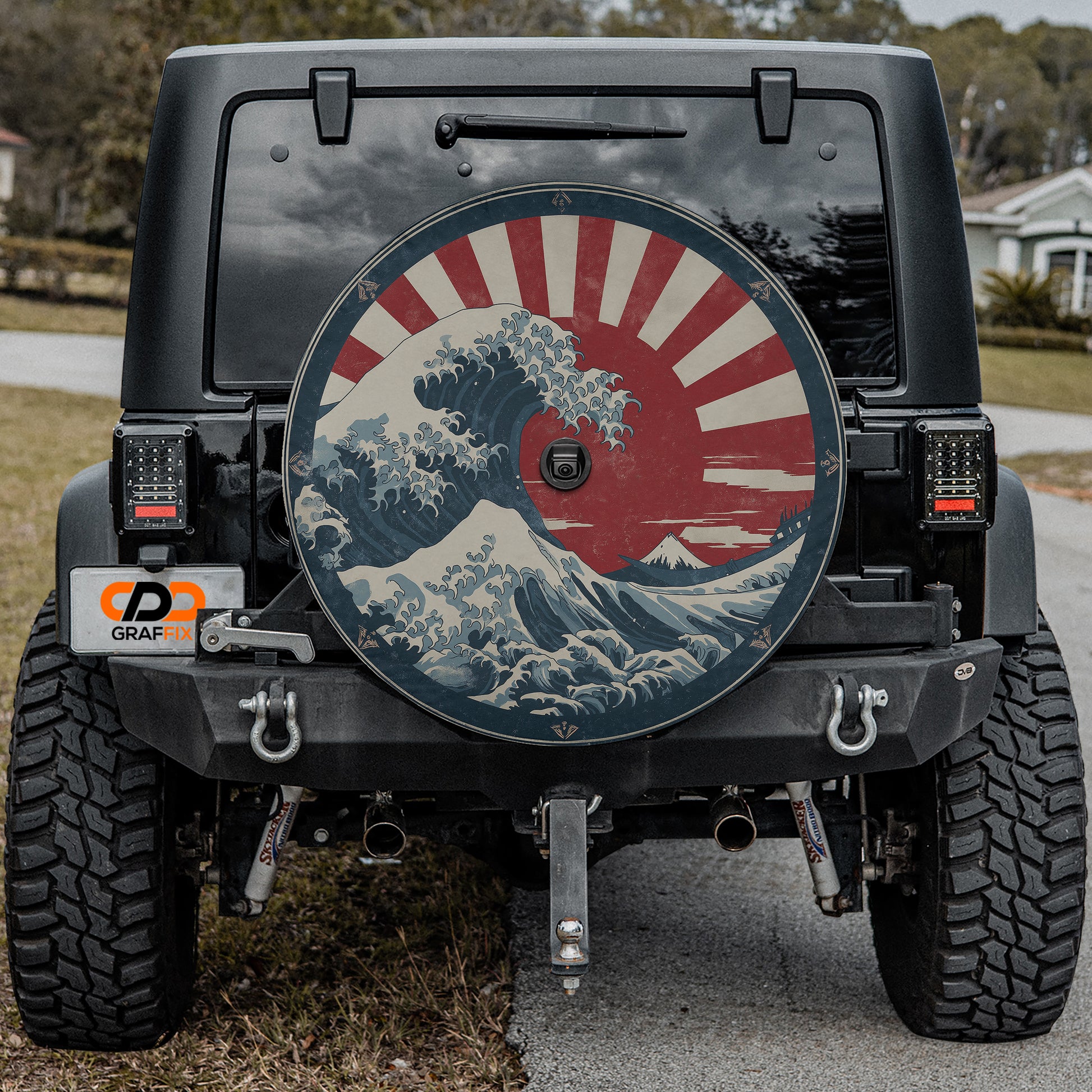 the rear of a black Jeep Wrangler with a large, colorful wheel cover featuring a wave design and a red and white sun.