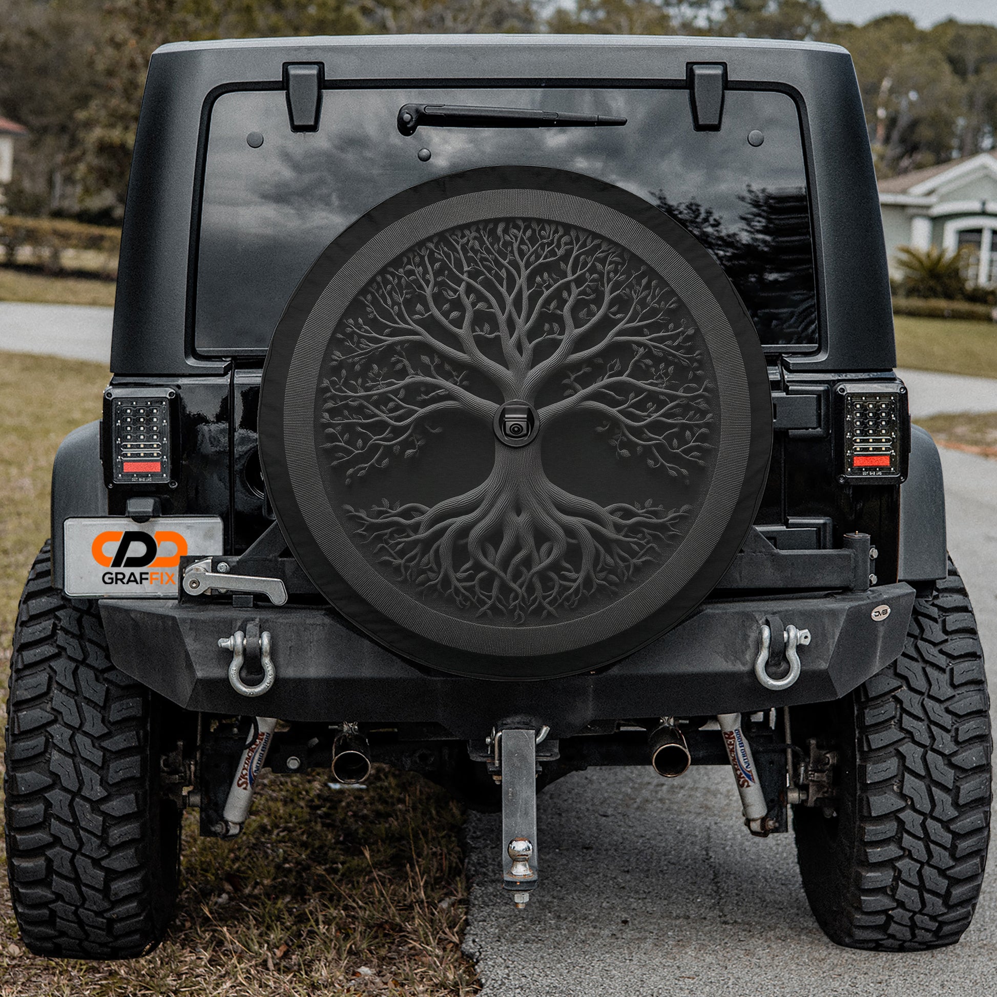 the rear of a black Jeep Wrangler with a large tree-like design on the spare tire cover.