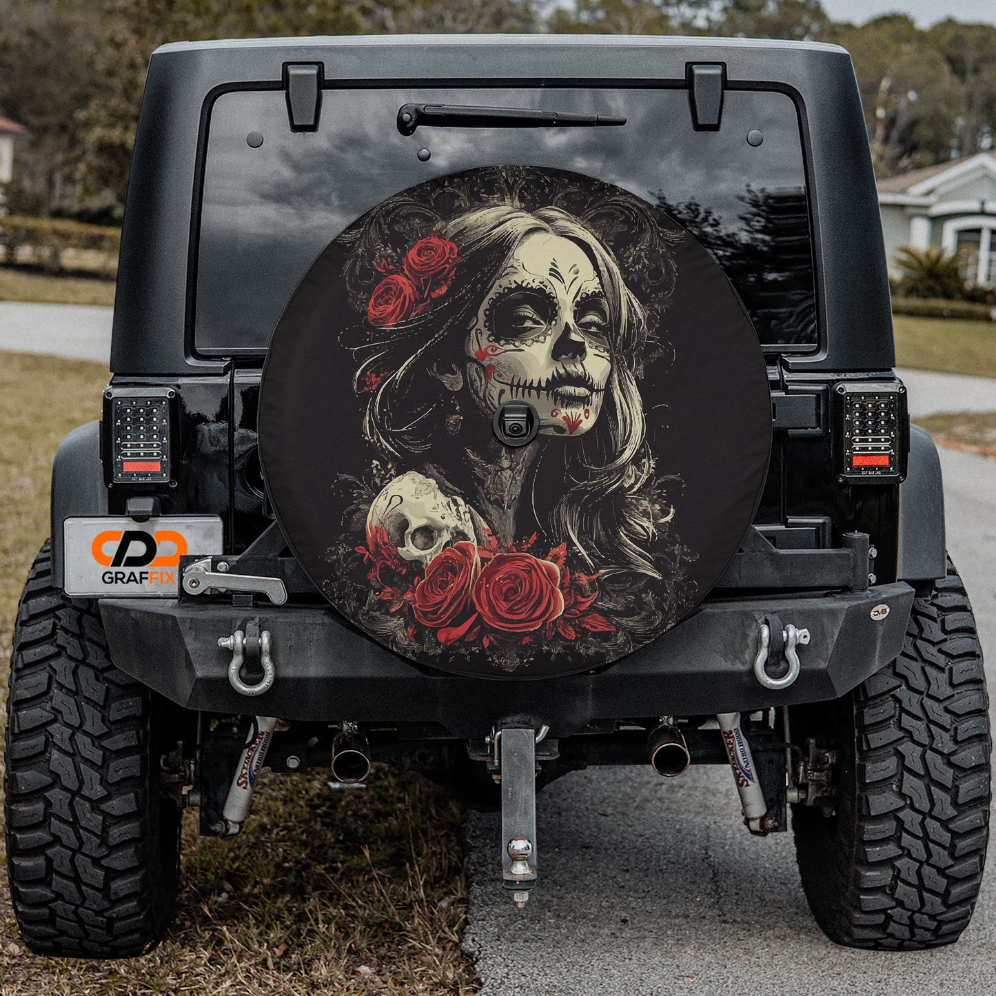 the back of a black Jeep Wrangler with a large, decorative wheel cover featuring a skull and floral design.