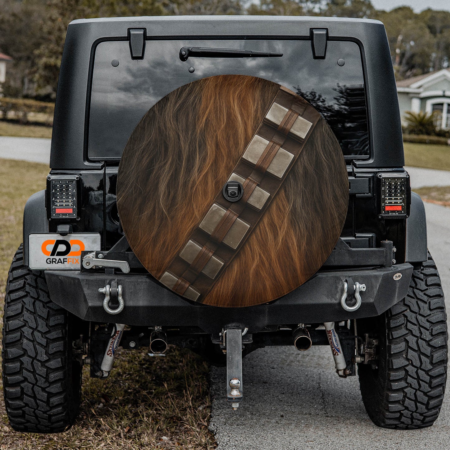 the back of a black Jeep Wrangler with a large wheel cover featuring Chewbacca's signature design.