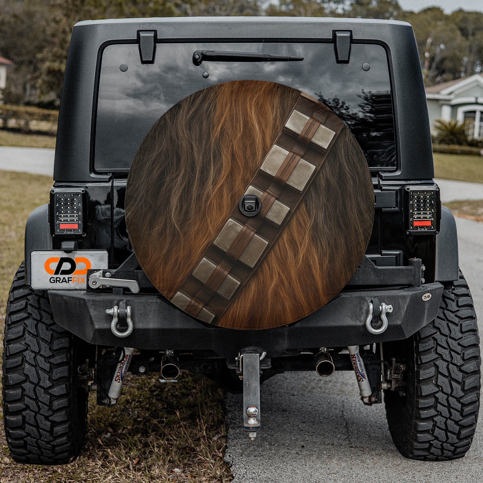 the back of a black Jeep Wrangler with a large wheel cover featuring Chewbacca's signature design.