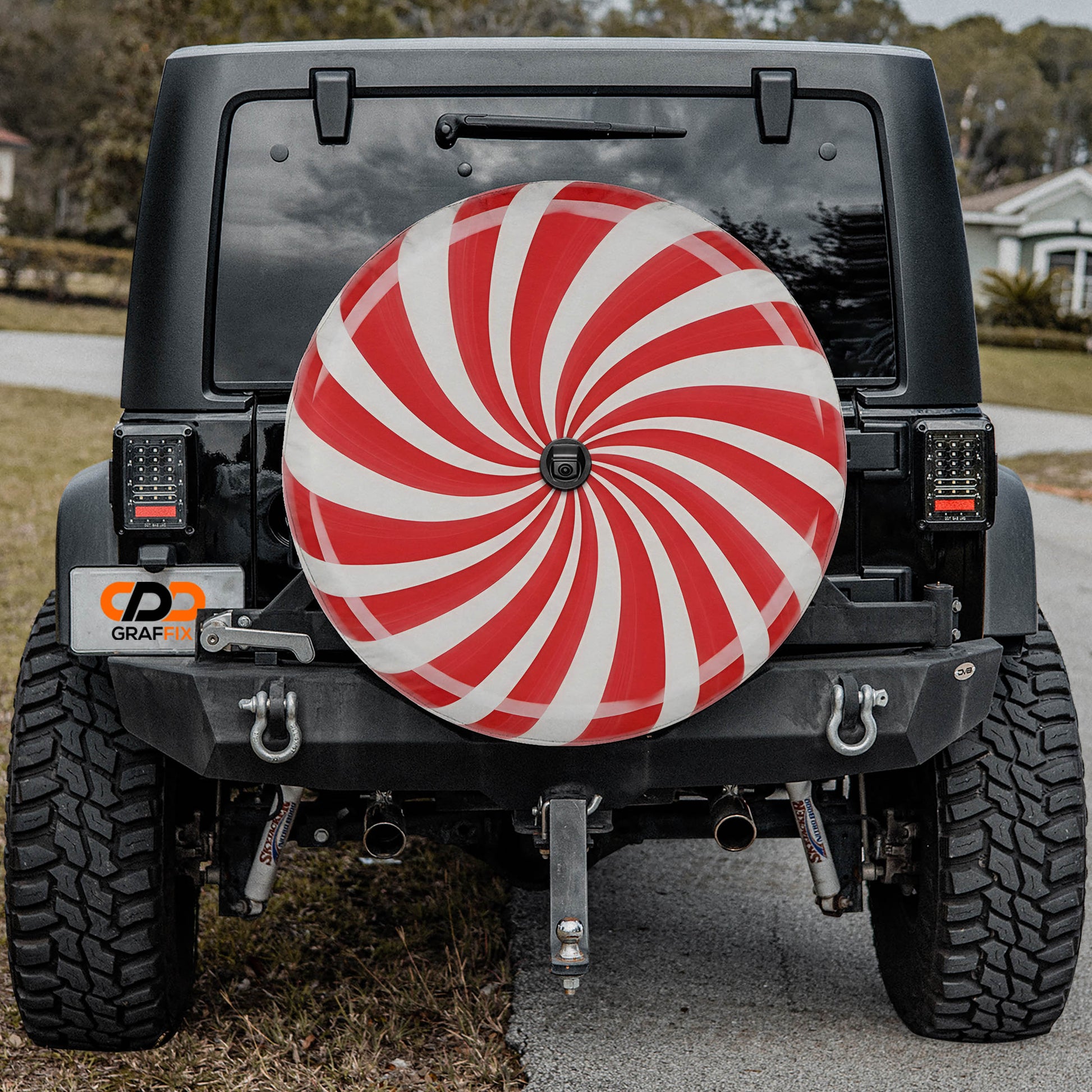 a black Jeep Wrangler with a large red and white tire cover attached to the rear of the vehicle.