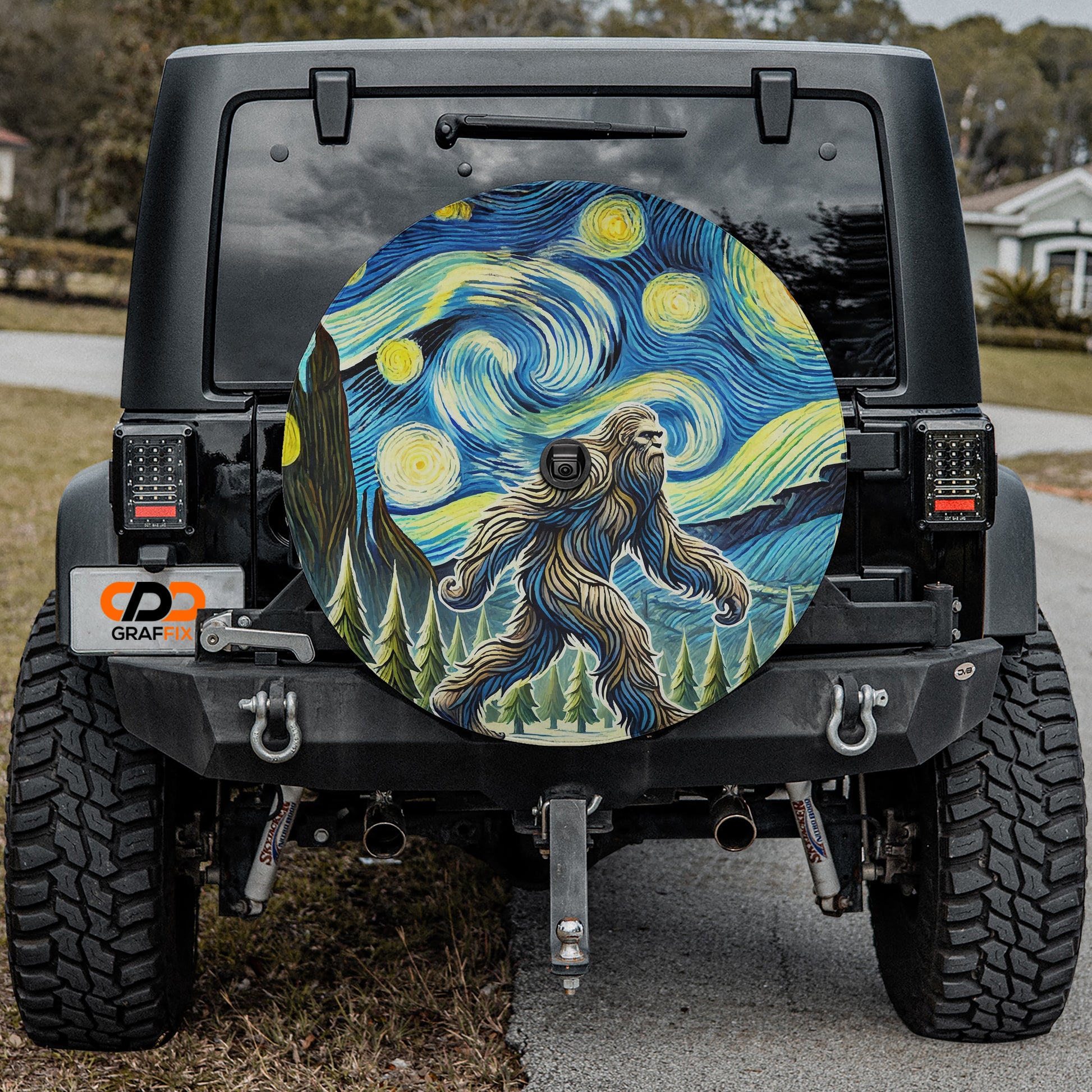 a black Jeep Wrangler with a large, colorful wheel cover depicting a man-like figure against a starry night sky background.