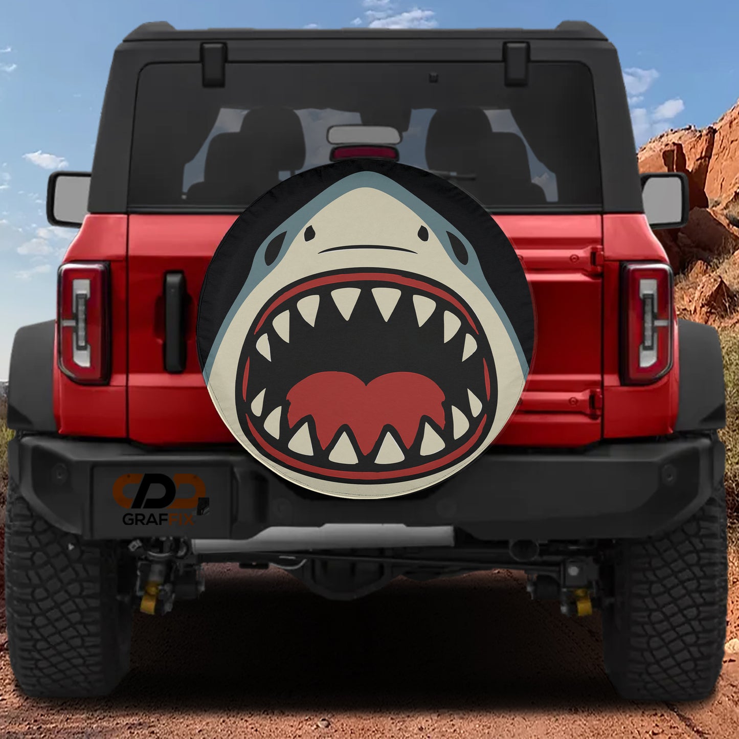 A red Jeep Wrangler with a shark-themed spare tire cover on the rear.