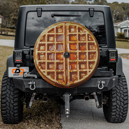 a black Jeep Wrangler with a waffle-shaped spare tire mounted on the rear of the vehicle.