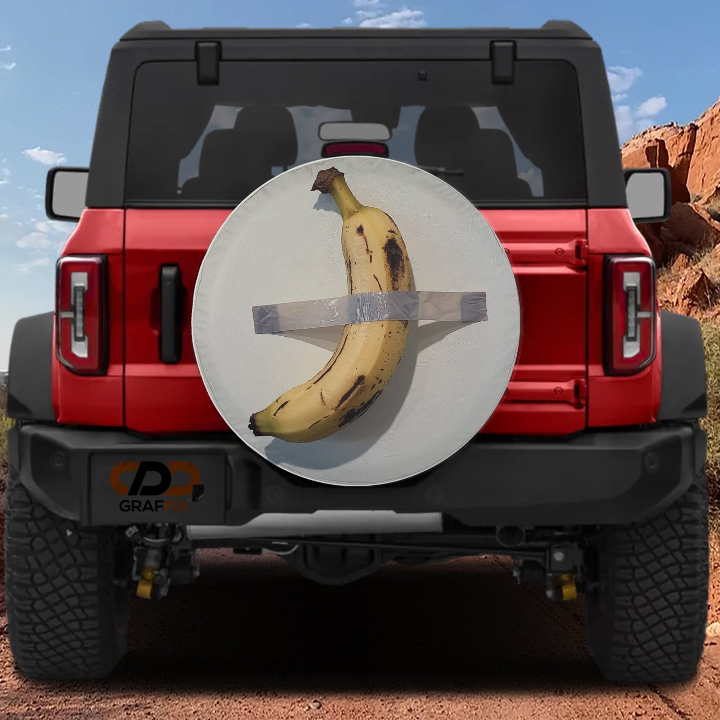 a red Jeep Wrangler with a banana taped to the rear bumper, against a backdrop of a rocky landscape.