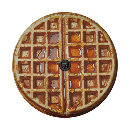 A waffle with syrup dripping from it, placed on a white background.