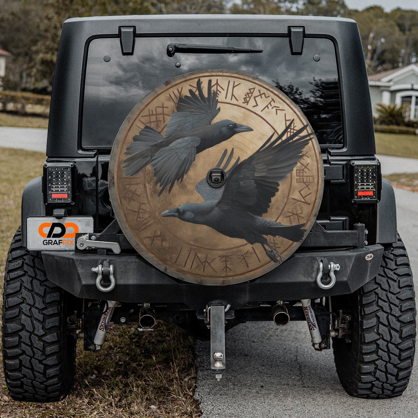 the back of a black Jeep Wrangler with a large, circular chrome wheel cover featuring a bird design.