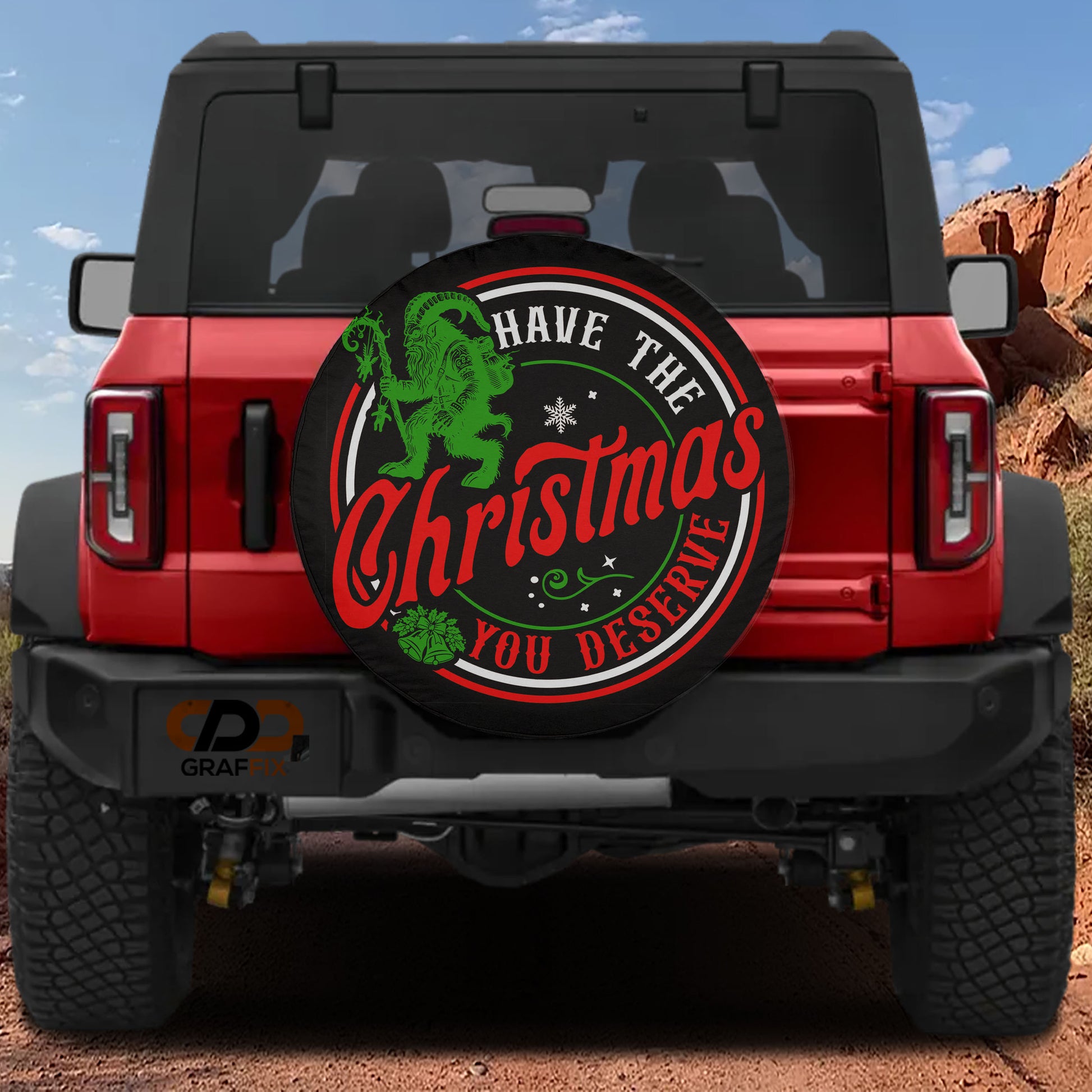 A red Jeep Wrangler with a large Christmas-themed spare tire attached to the rear.