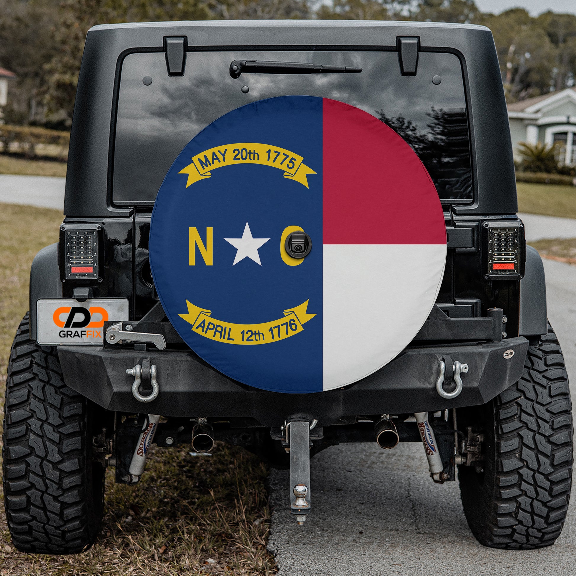 the back of a black Jeep Wrangler with a large round spare tire cover featuring the state flag of North Carolina.