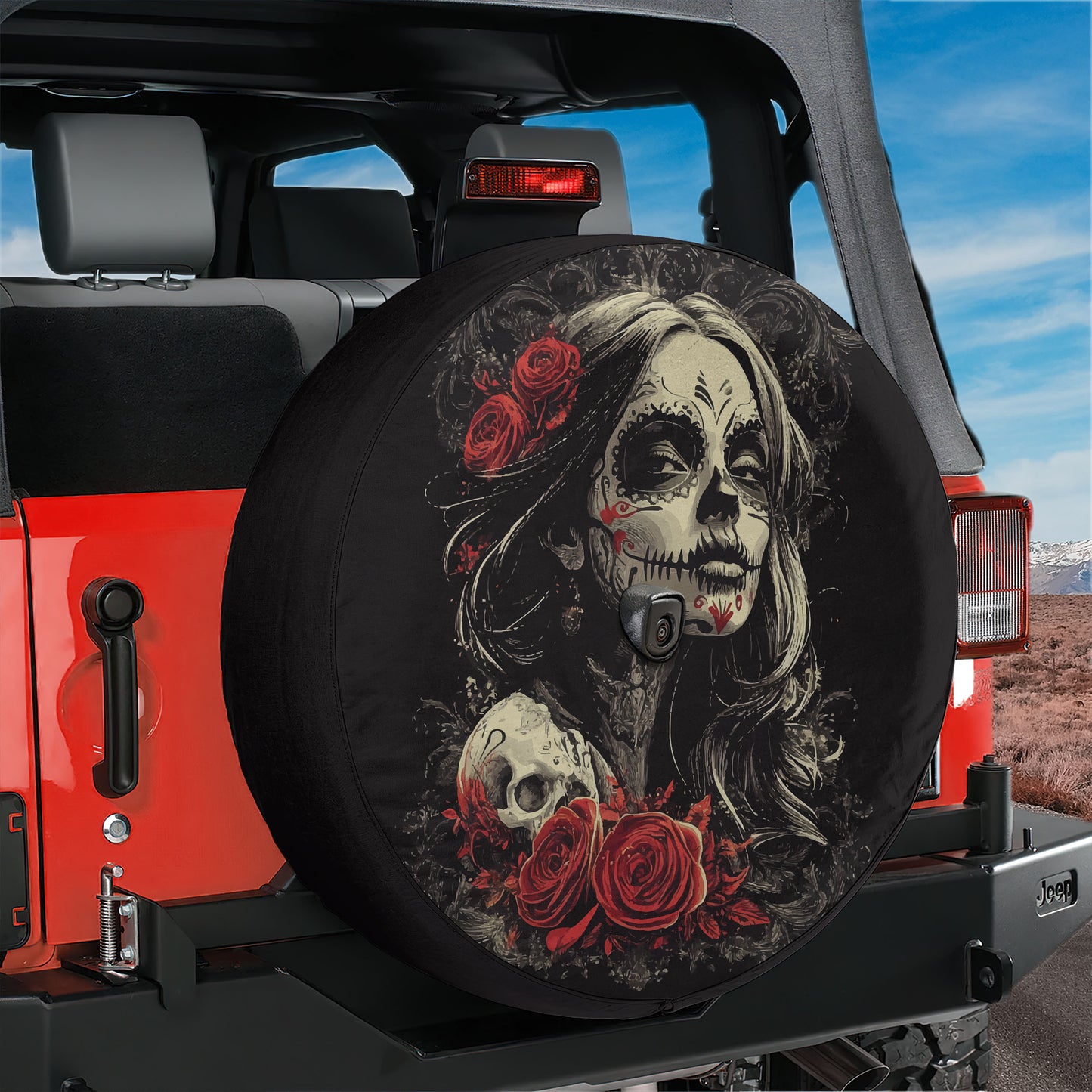 A black tire cover with a skull design and red roses on the back of a red Jeep.