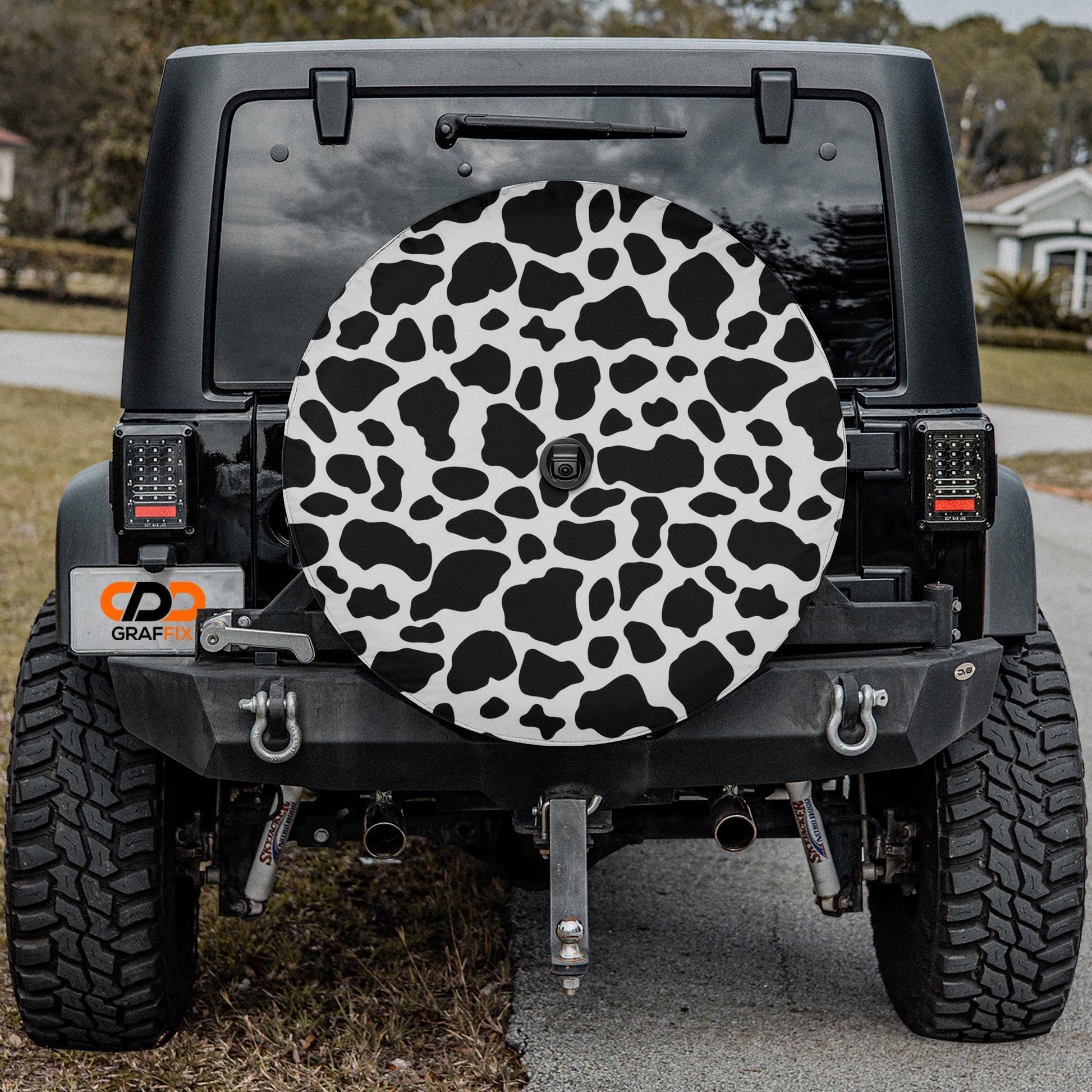 a black Jeep Wrangler with a cow print rear cover attached to it.