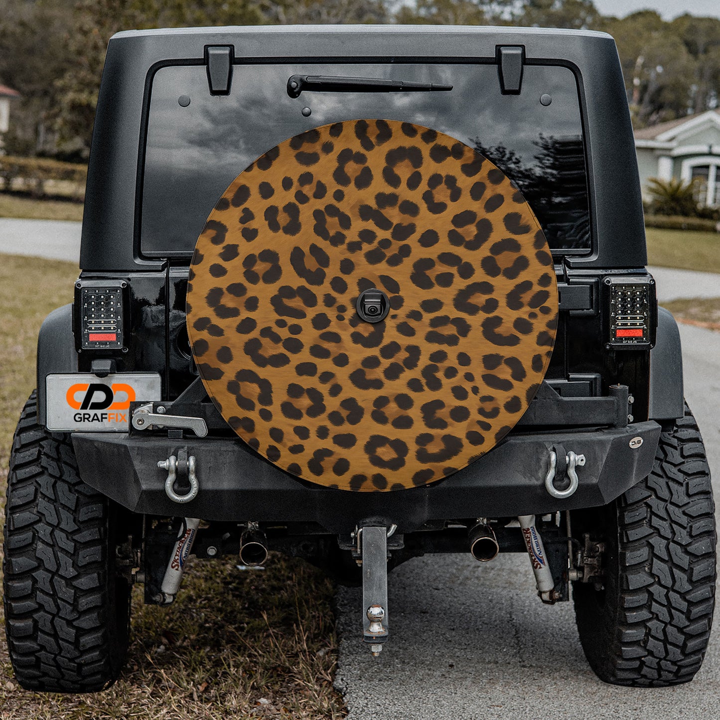 a black Jeep Wrangler with a large leopard print spare tire attached to the rear of the vehicle.