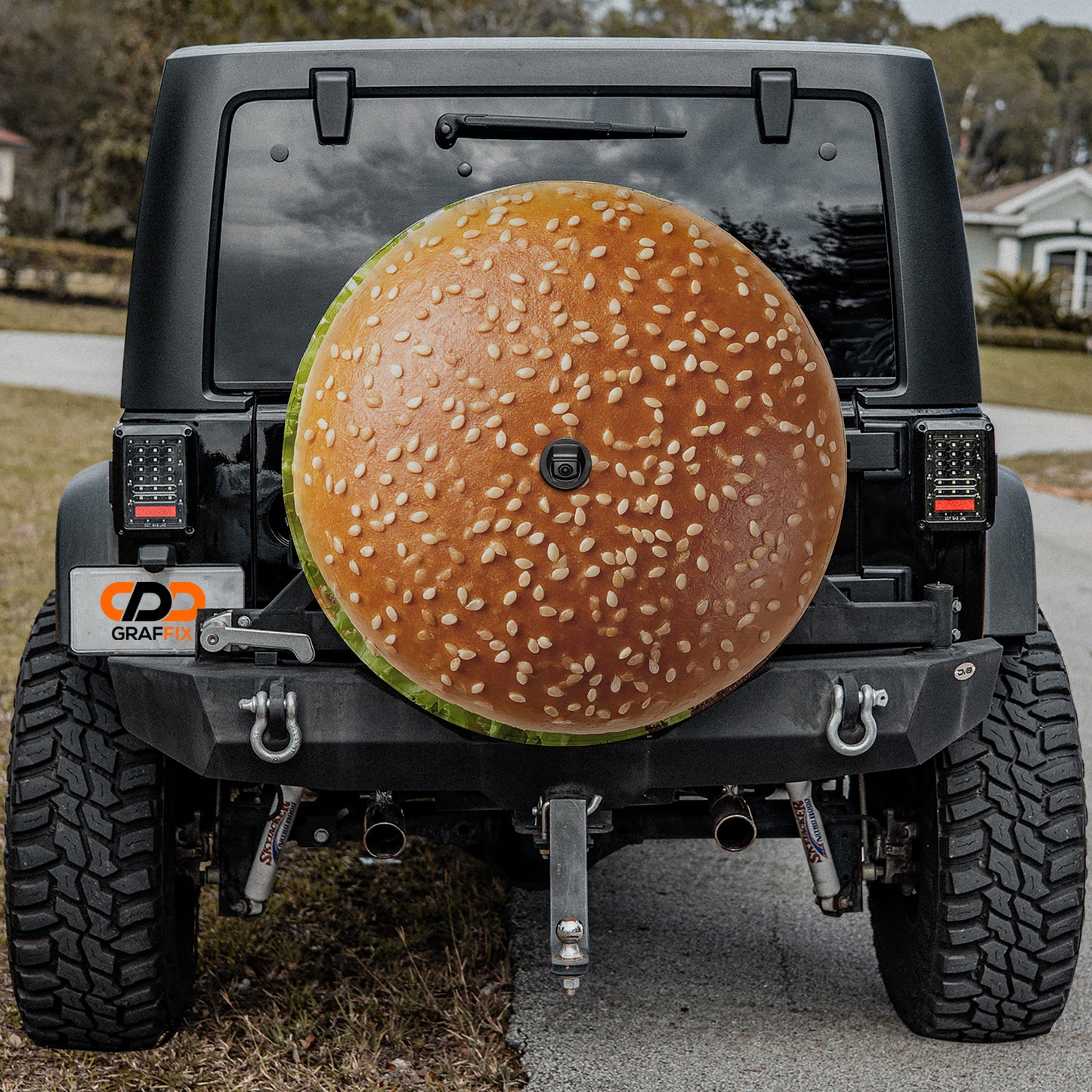 a black Jeep Wrangler with a large hamburger bun attached to the rear of the vehicle.