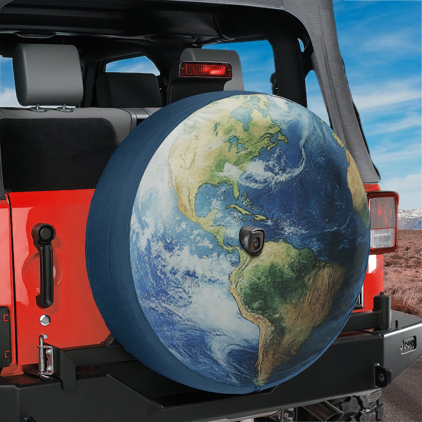 A large globe-shaped spare tire is attached to the rear of a red Jeep, with a desert landscape visible in the background.