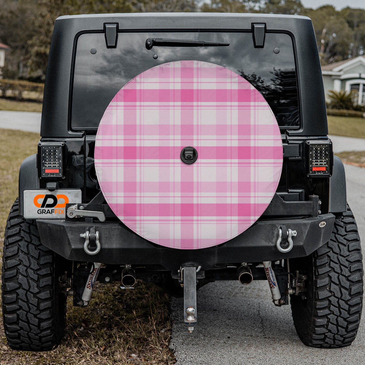 the rear of a black Jeep Wrangler with a large pink checkered wheel cover attached to it.