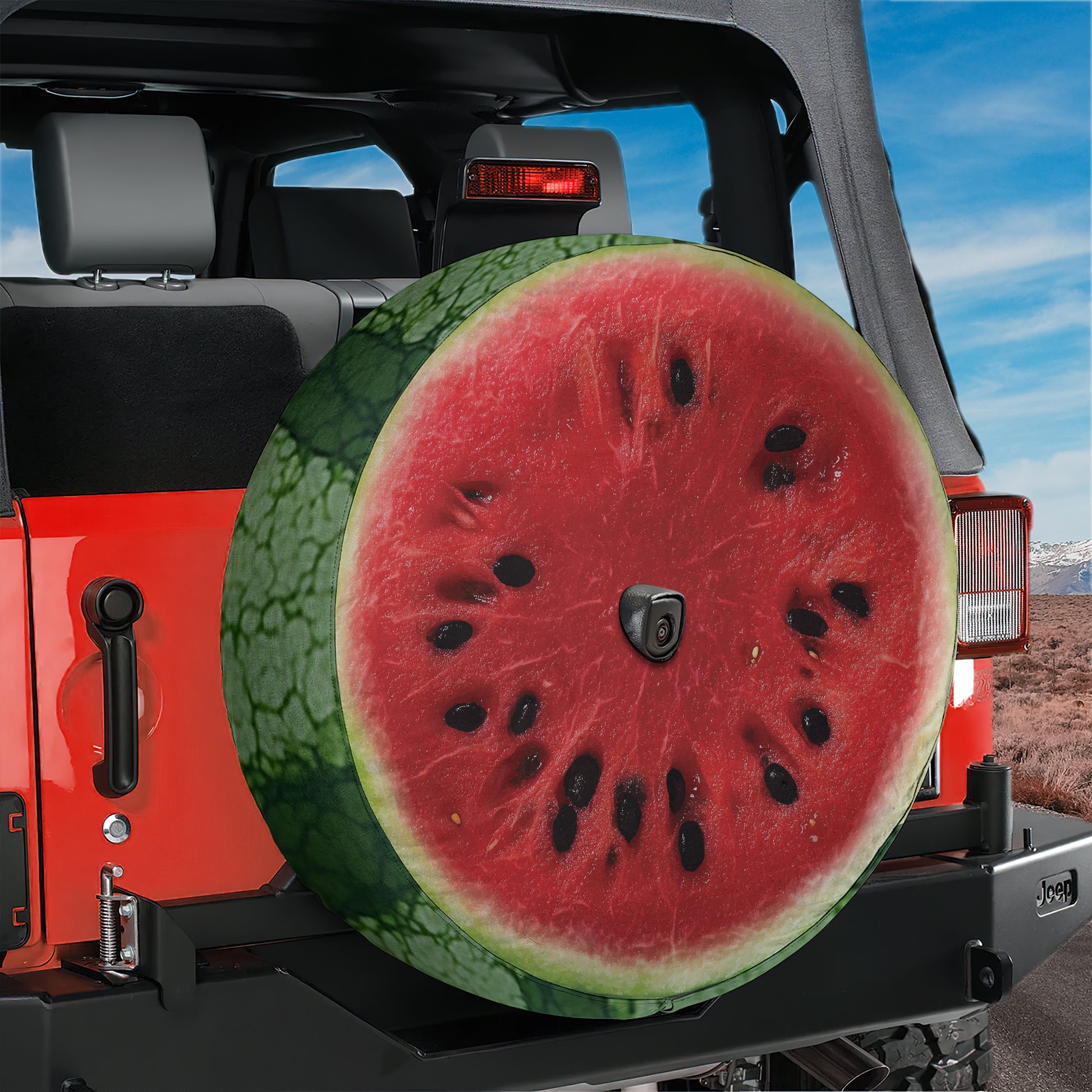 A red Jeep Wrangler with a large watermelon-shaped spare tire attached to the rear.