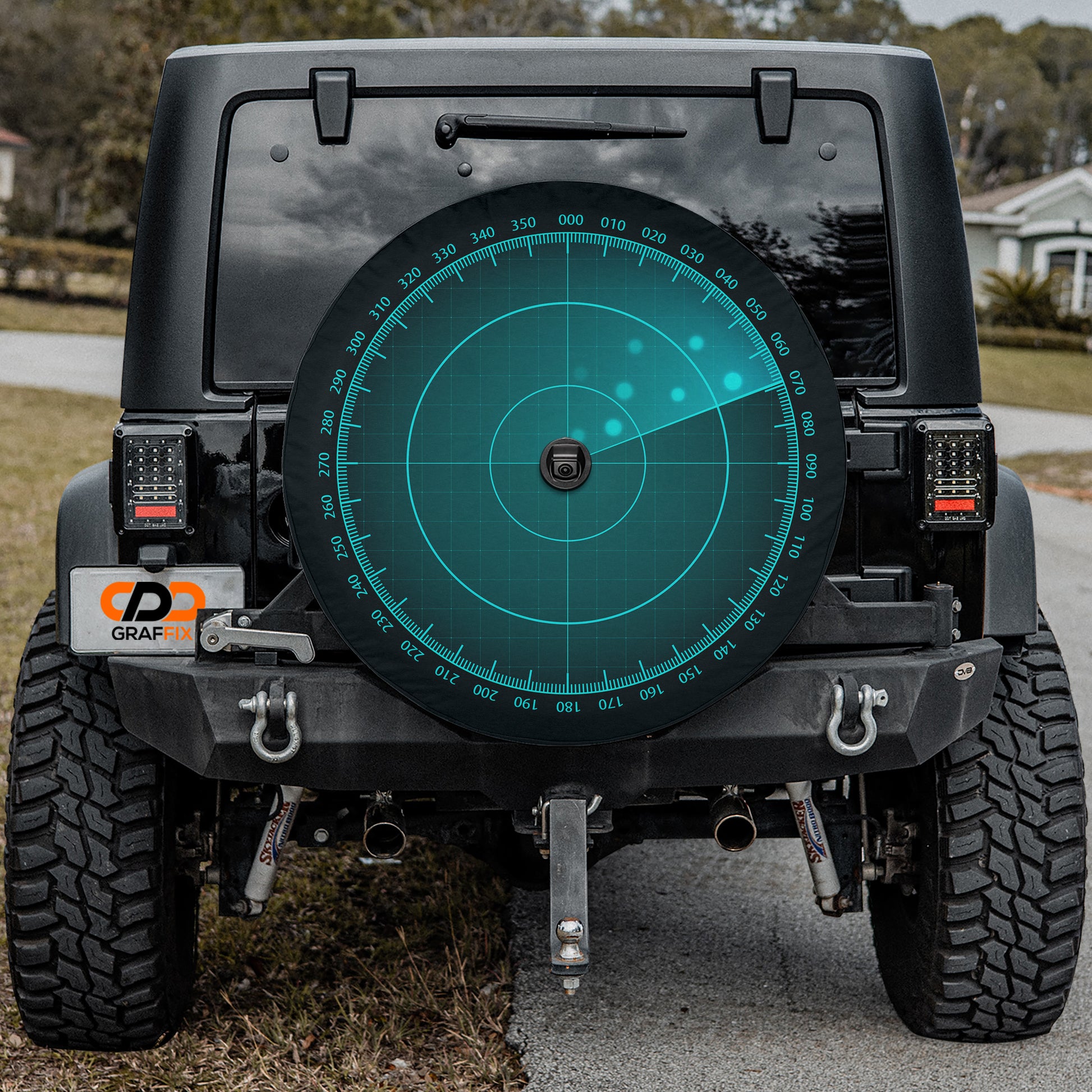 the rear of a black Jeep Wrangler with a large rear wheel cover featuring a radar-like design.