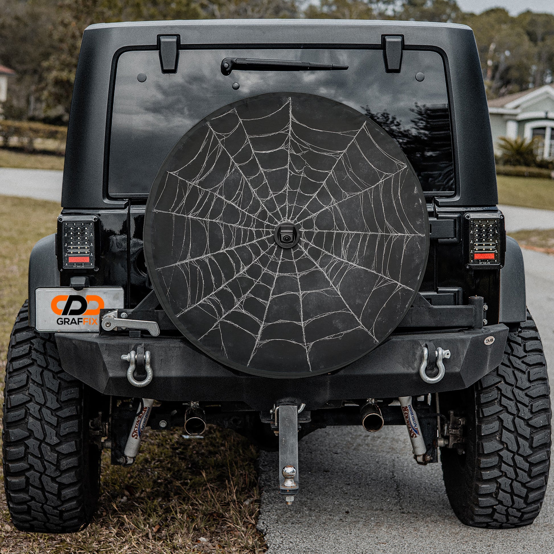 a black Jeep Wrangler with a large spider web decal on the rear window.