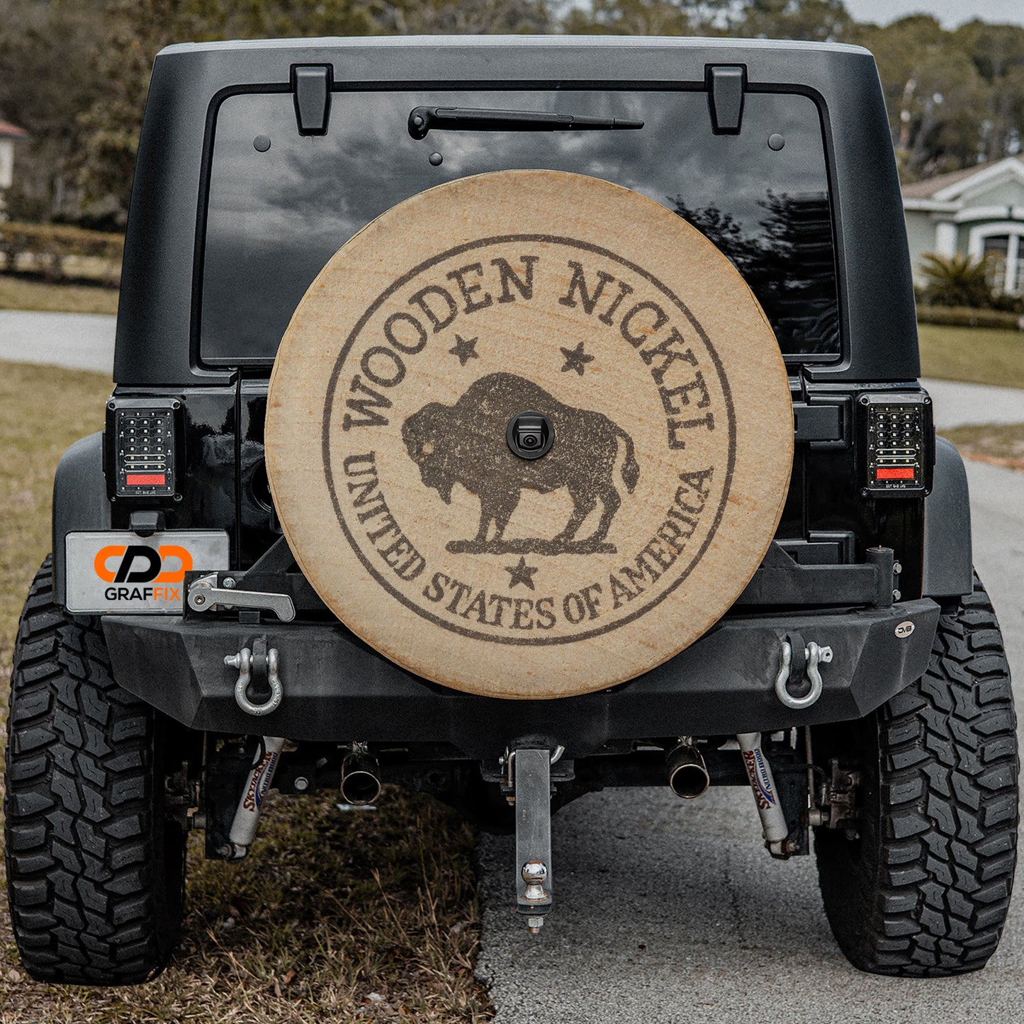 a black Jeep Wrangler with a large wooden spare tire attached to the rear of the vehicle.
