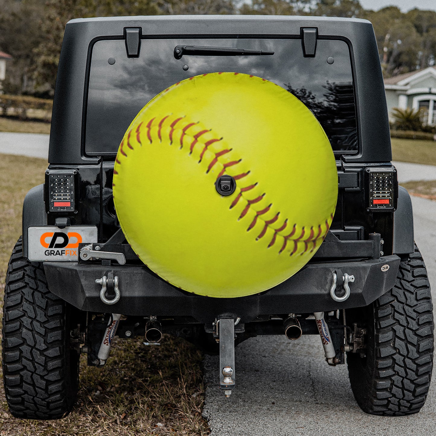 a black Jeep Wrangler with a large yellow softball attached to the rear bumper.
