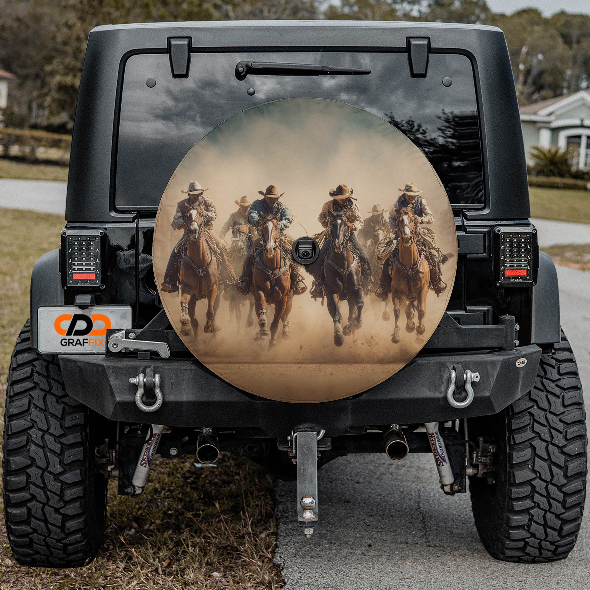 a black Jeep Wrangler with a large rear wheel cover depicting a group of people riding horses.