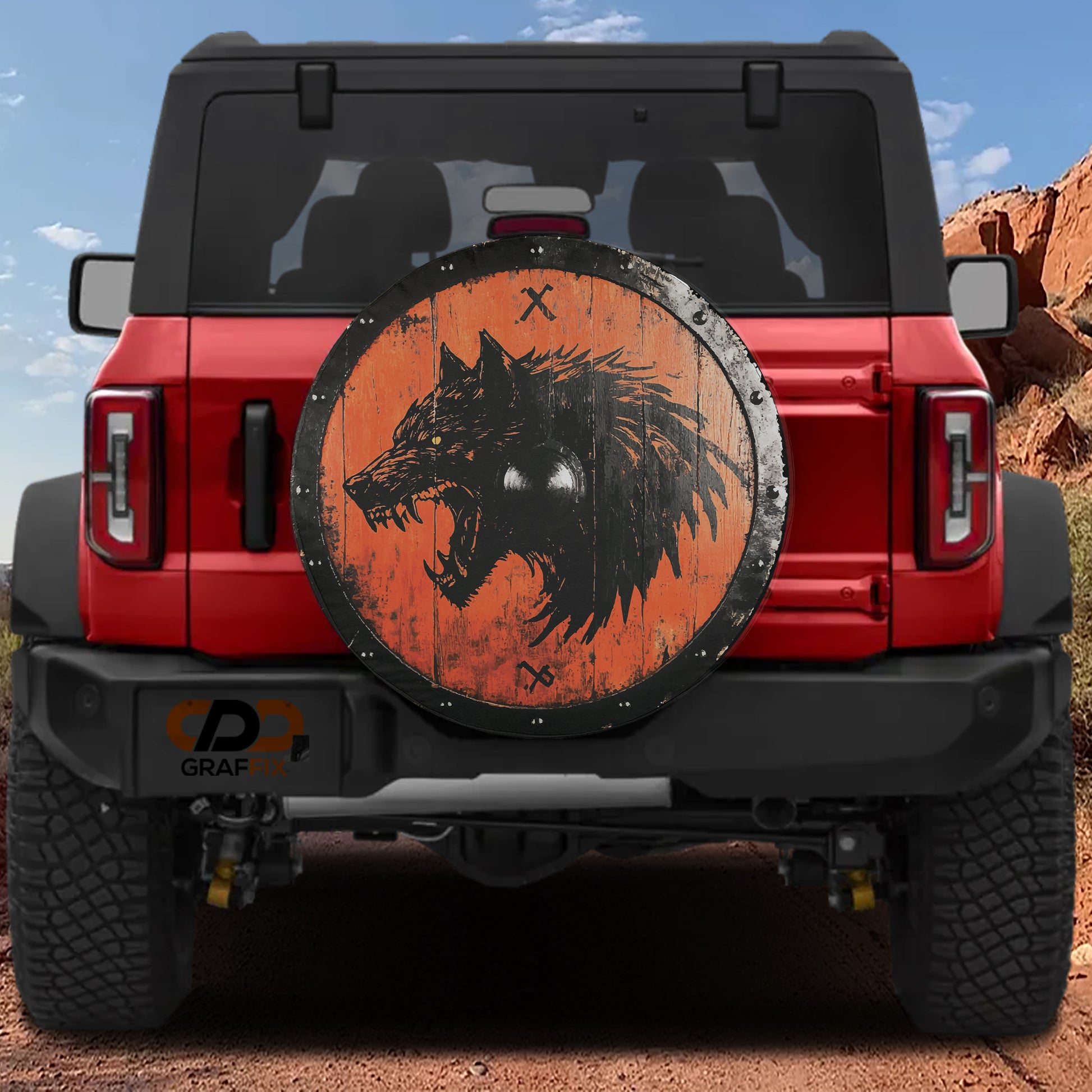 a red Jeep Wrangler with a large wooden shield on the rear window, depicting a fierce-looking wolf.