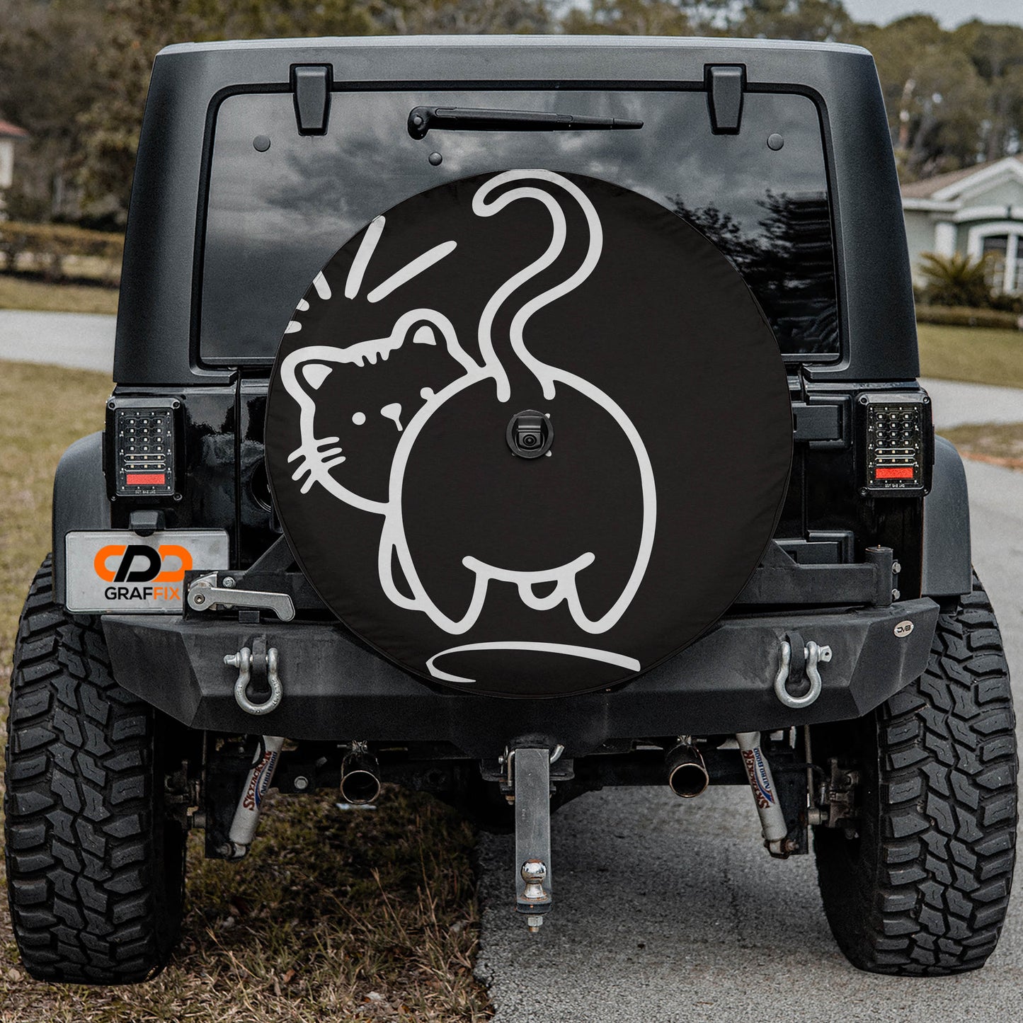 a black Jeep Wrangler with a large cat-shaped spare tire cover on the rear of the vehicle.