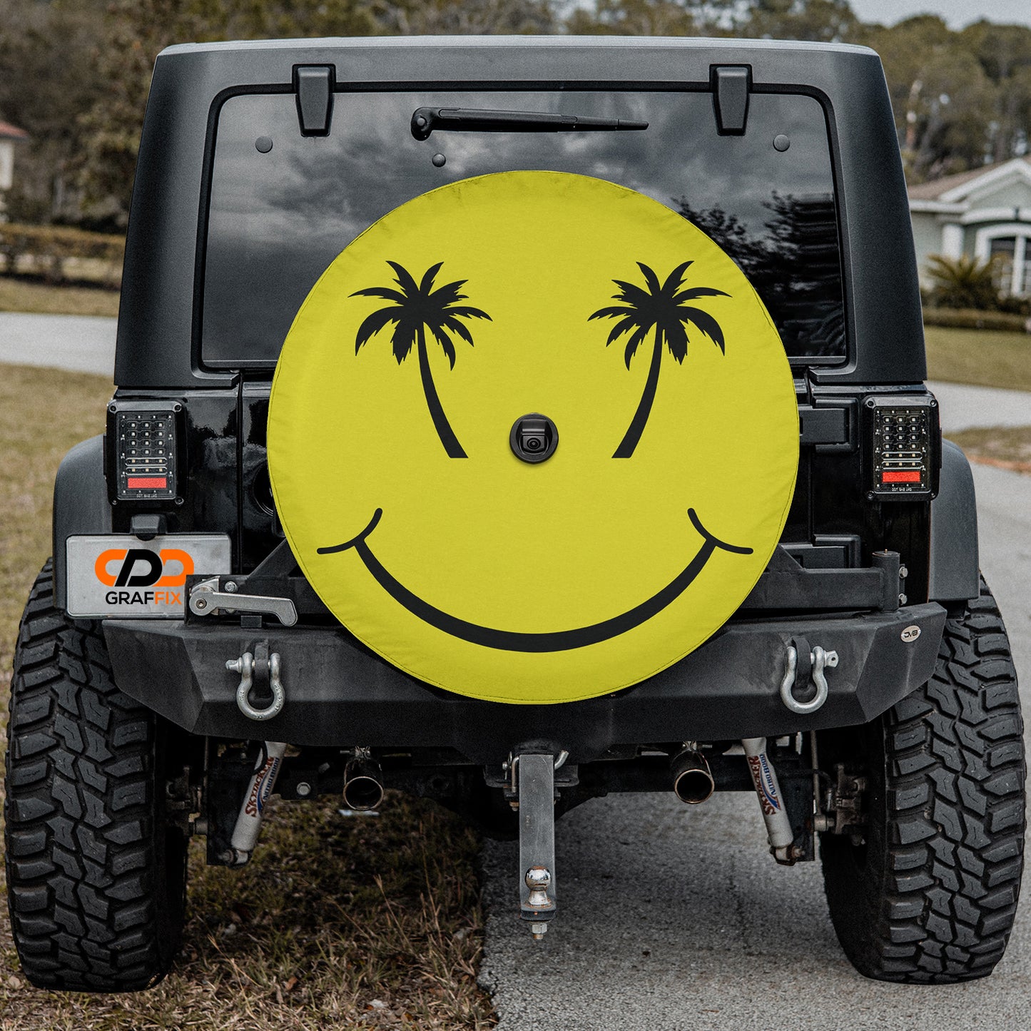 a black Jeep Wrangler with a large yellow smiley face decal on the rear window.