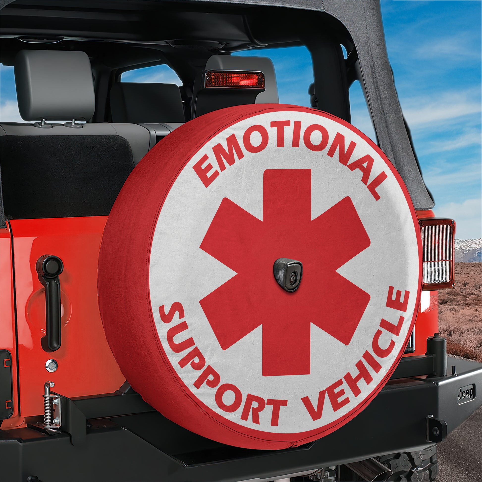 A red Jeep vehicle with a large tire cover that says "Emotional Support Vehicle" in white letters.