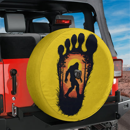 A yellow tire cover with a black silhouette of a Sasquatch, a mythical creature, is attached to the back of a red Jeep.