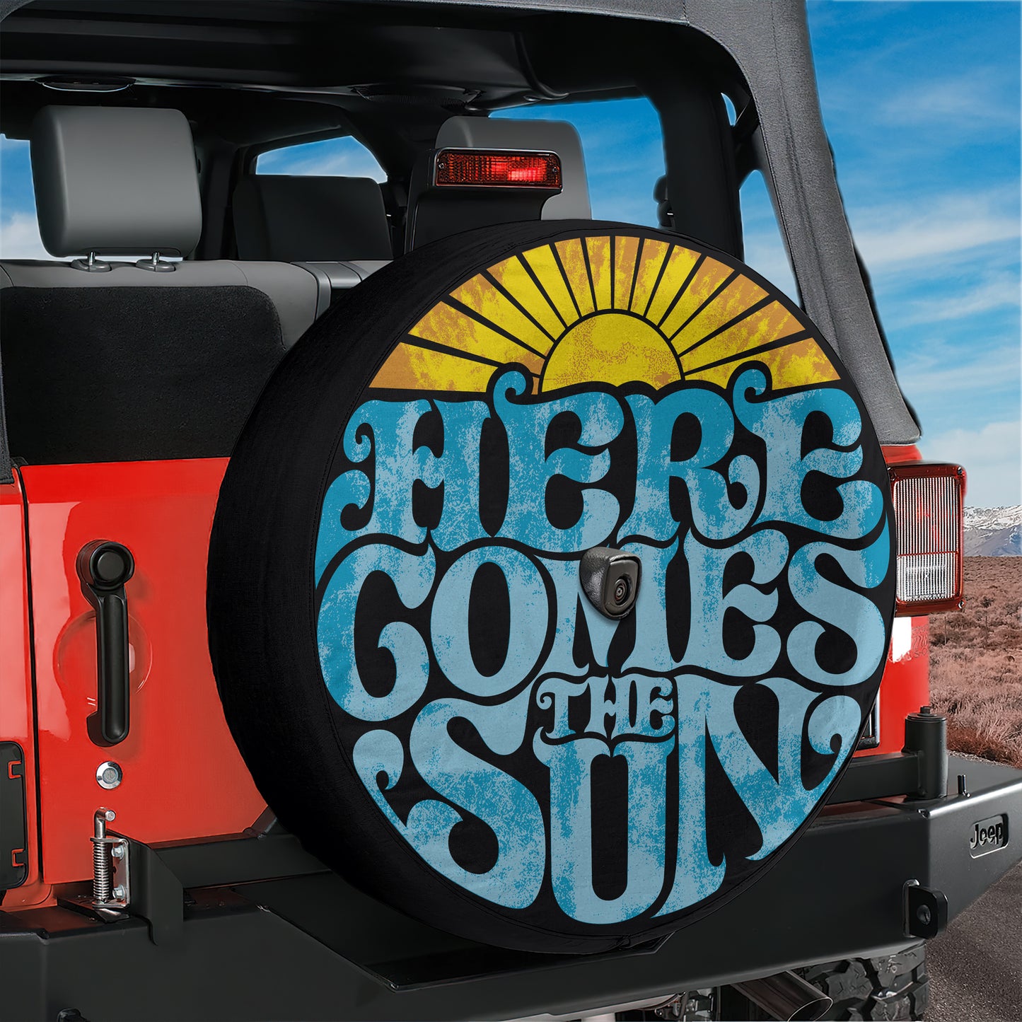 A red Jeep with a large sun-themed spare tire cover on the rear of the vehicle.