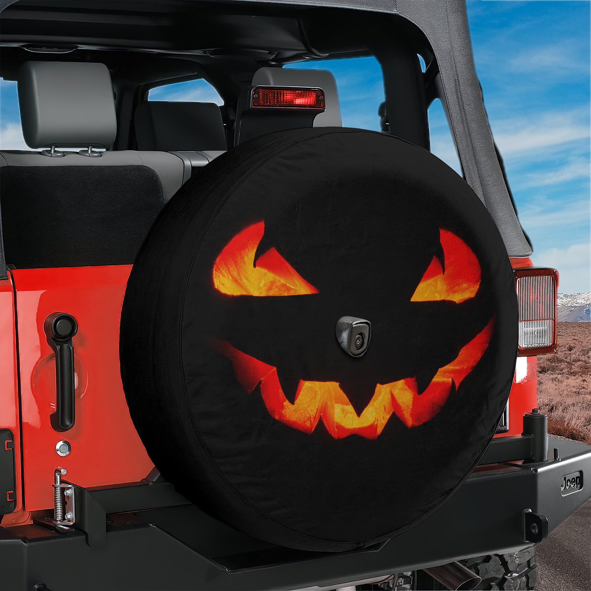 A Jeep Wrangler with a Halloween-themed spare tire cover featuring a jack-o-lantern design.