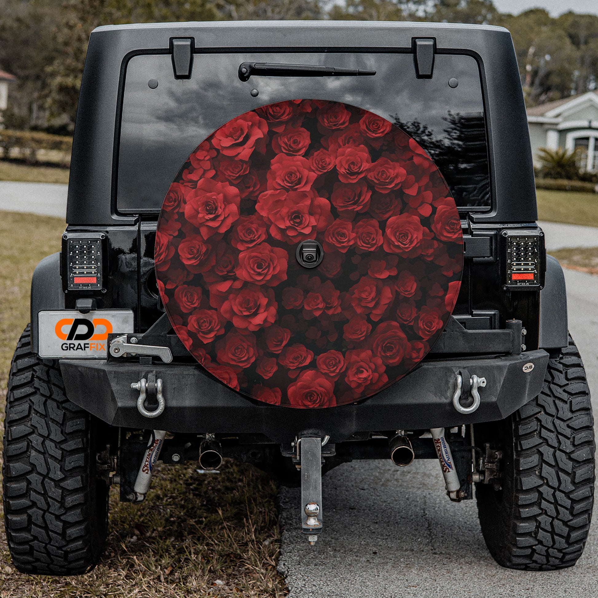 the rear of a black Jeep Wrangler with a large, round spare tire cover featuring a red rose design.