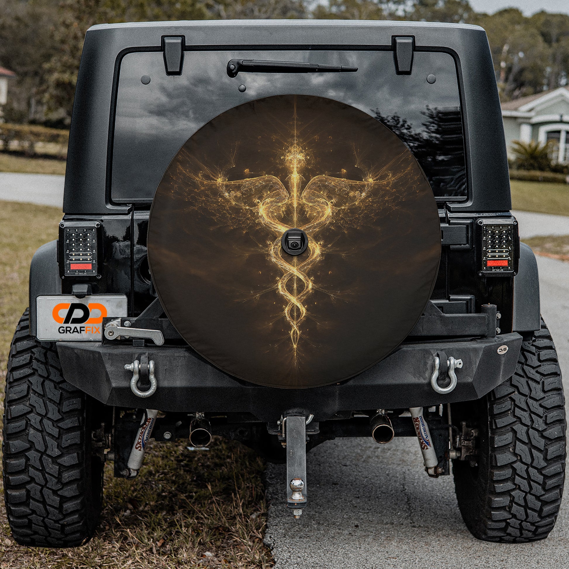 a black Jeep Wrangler with a large tire cover featuring a golden design on the back.