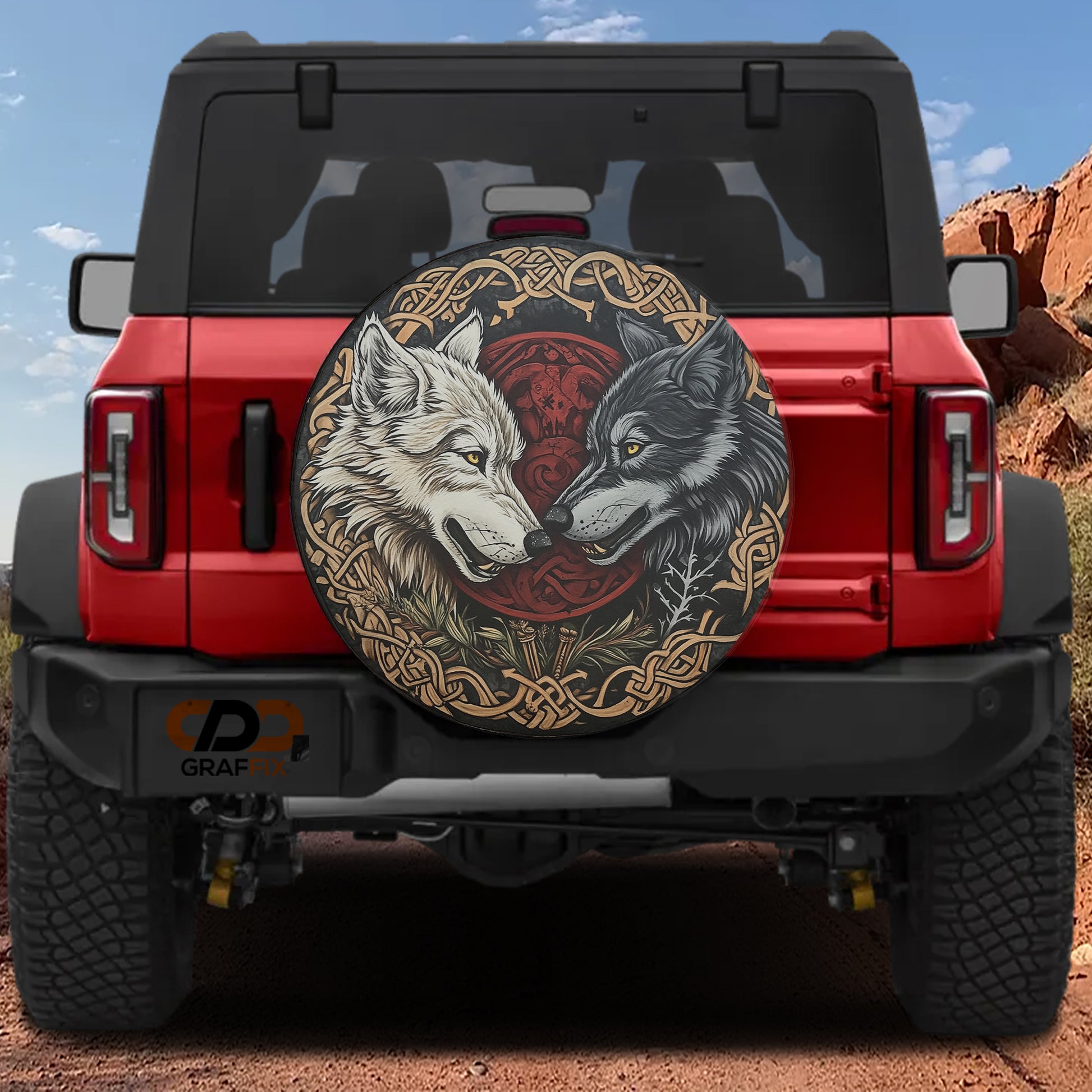 a red Jeep Wrangler with a large, decorative tire cover featuring two wolves facing each other.