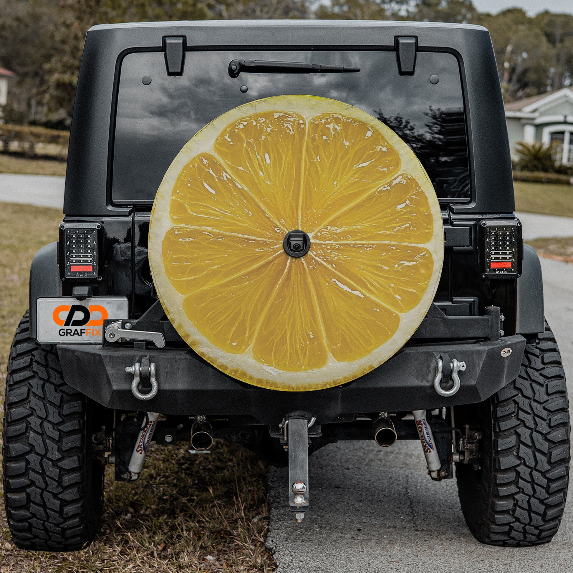 a black Jeep Wrangler with a large, vibrant yellow lemon sticker on the rear window.