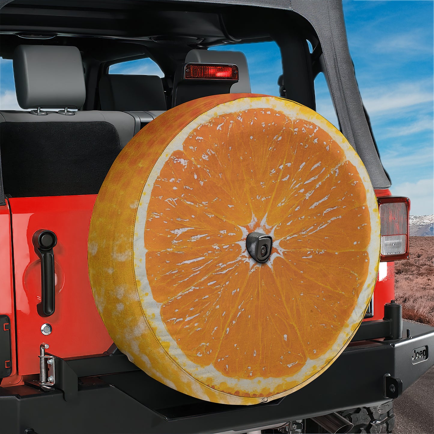 A large orange-colored tire cover is attached to the rear of a red Jeep vehicle, providing a unique and eye-catching design.