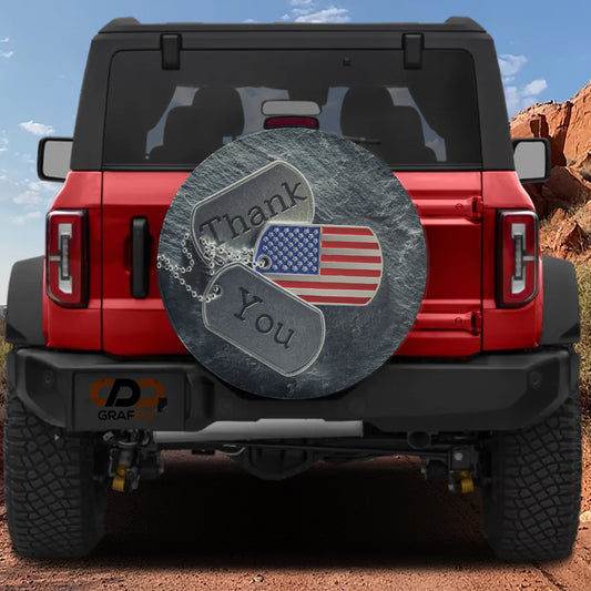 the back of a red Jeep Wrangler with a patriotic-themed spare tire cover attached to it. The cover features an American flag and the words "Thank You" on it.