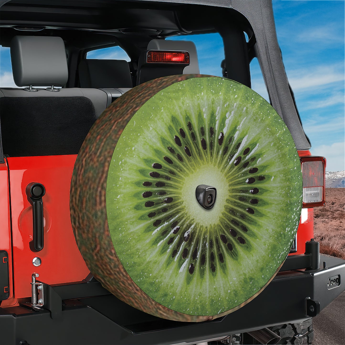 A red Jeep Wrangler with a large kiwi fruit-shaped spare tire attached to the rear.
