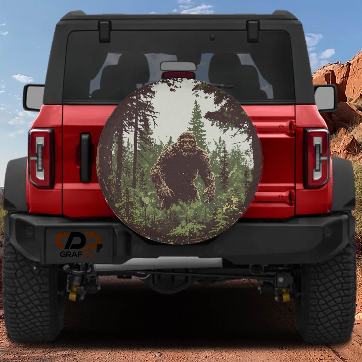 a red Jeep Wrangler with a large round decal on the rear window depicting a giant Sasquatch.